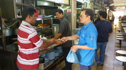 Customer paying for his packet of biryani at the Indian stall at the hawker center.