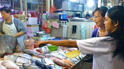 A Filipina buying fish from a Singaporean vendor as part of her weekly routine at the fresh food market in Boon Lay.