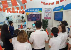 In the service hall of the China Mobile Company, staff are holding a national flag and watching the ceremony of the celebration.
